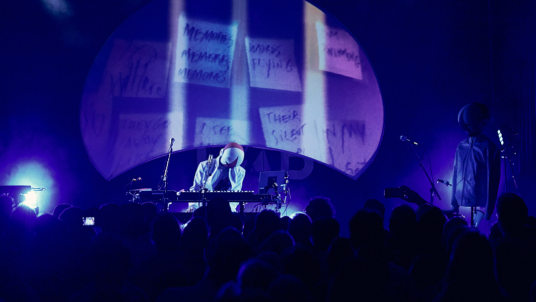 Concert sous éclairage violet avec projections sur scène