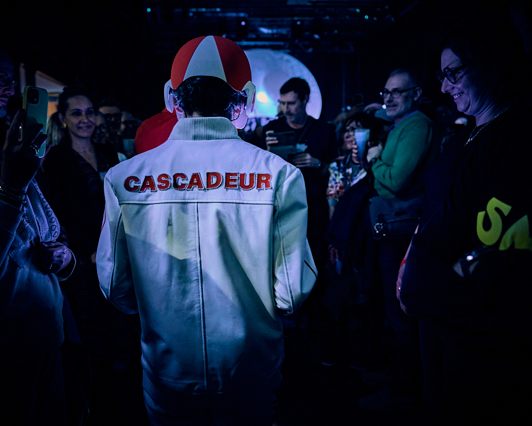 Cascadeur de dos en veste blanche siglée, face au public
