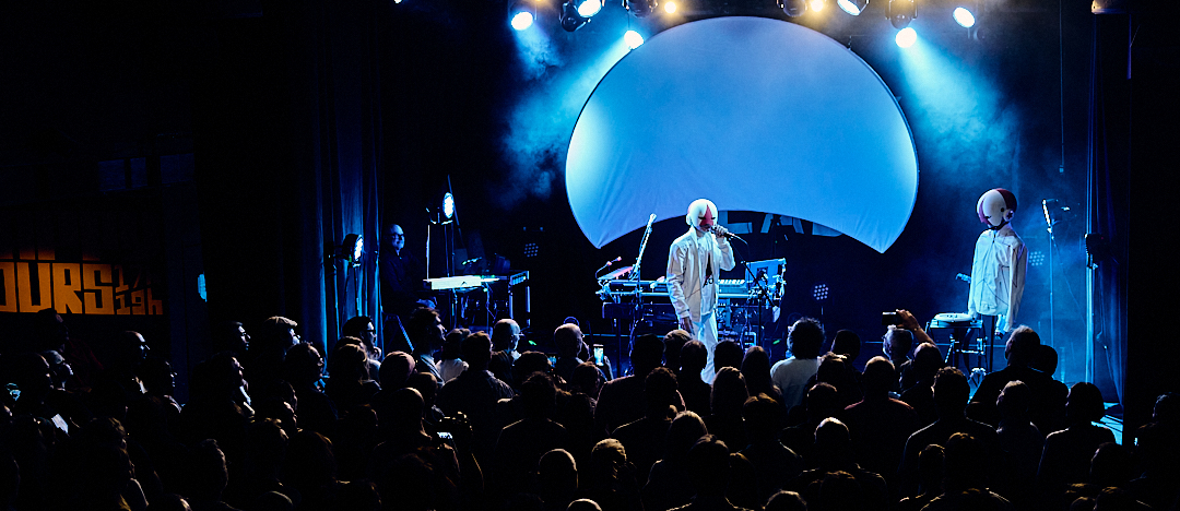 Vue panoramique du concert, deux silhouettes sur scène