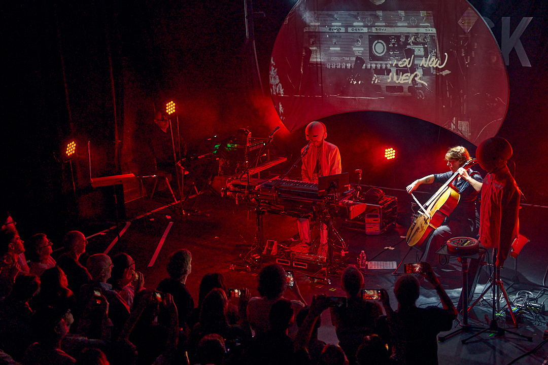 Cascadeur, violoncelliste et second personnage masqué sous lumière rouge